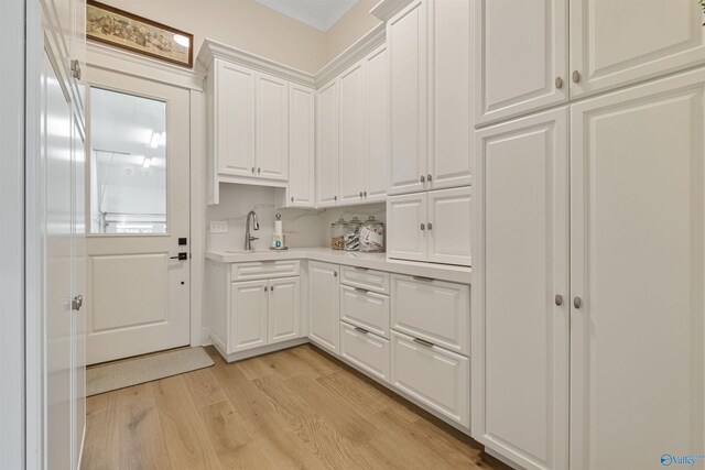 kitchen featuring sink, white cabinetry, and light wood-type flooring