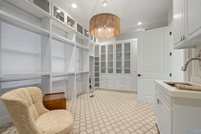 walk in closet featuring light tile patterned flooring, sink, and a notable chandelier