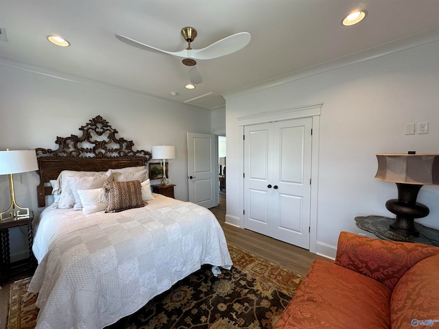 bedroom featuring wood-type flooring, crown molding, a closet, and ceiling fan