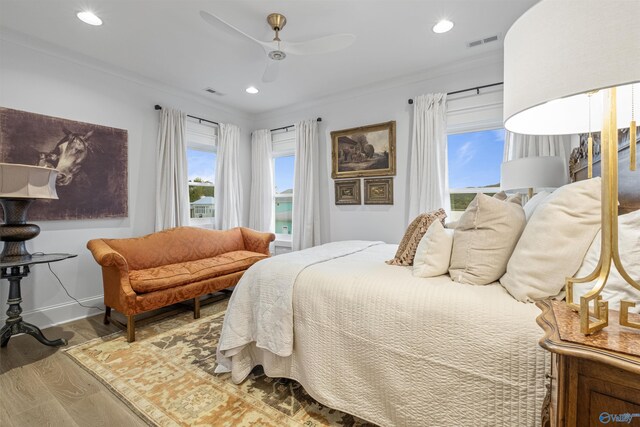 bedroom featuring ornamental molding, multiple windows, hardwood / wood-style floors, and ceiling fan