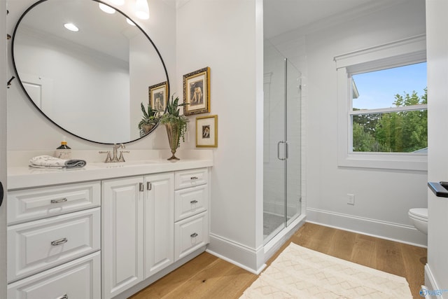 bathroom featuring hardwood / wood-style flooring, a shower with door, toilet, and vanity