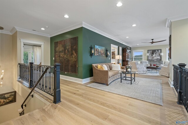 living room with a healthy amount of sunlight, crown molding, light wood-type flooring, and ceiling fan