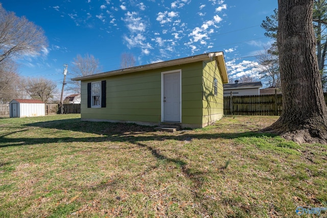 rear view of property with a yard and a storage shed