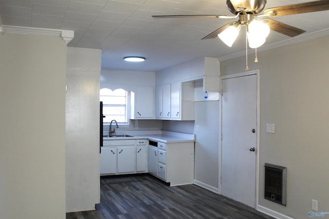 kitchen with sink, white cabinetry, heating unit, and crown molding