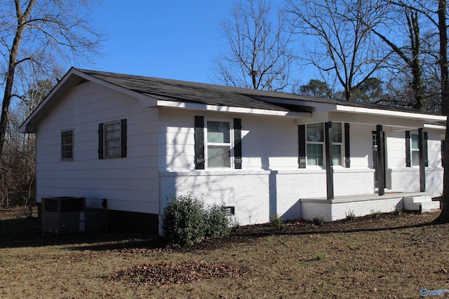 view of home's exterior with a lawn, central AC, and covered porch