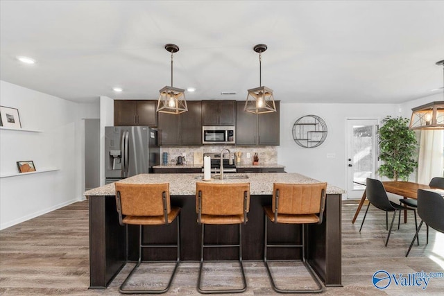 kitchen featuring stainless steel appliances, tasteful backsplash, sink, a center island with sink, and dark brown cabinets