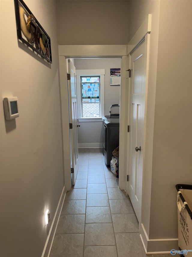 hall featuring light tile patterned floors, washer / dryer, and baseboards