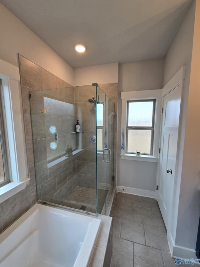 full bathroom with a shower stall, a bath, and baseboards