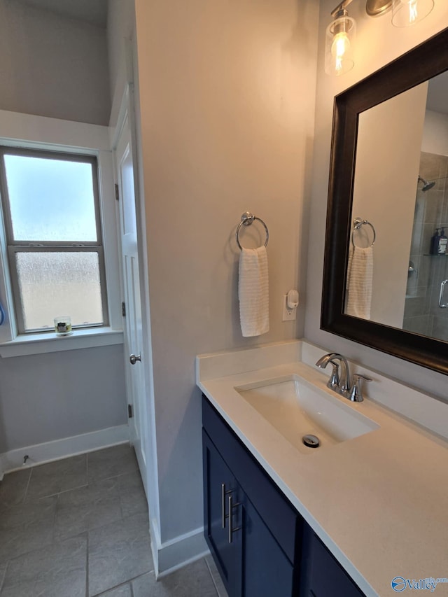 bathroom with baseboards, vanity, and a tile shower