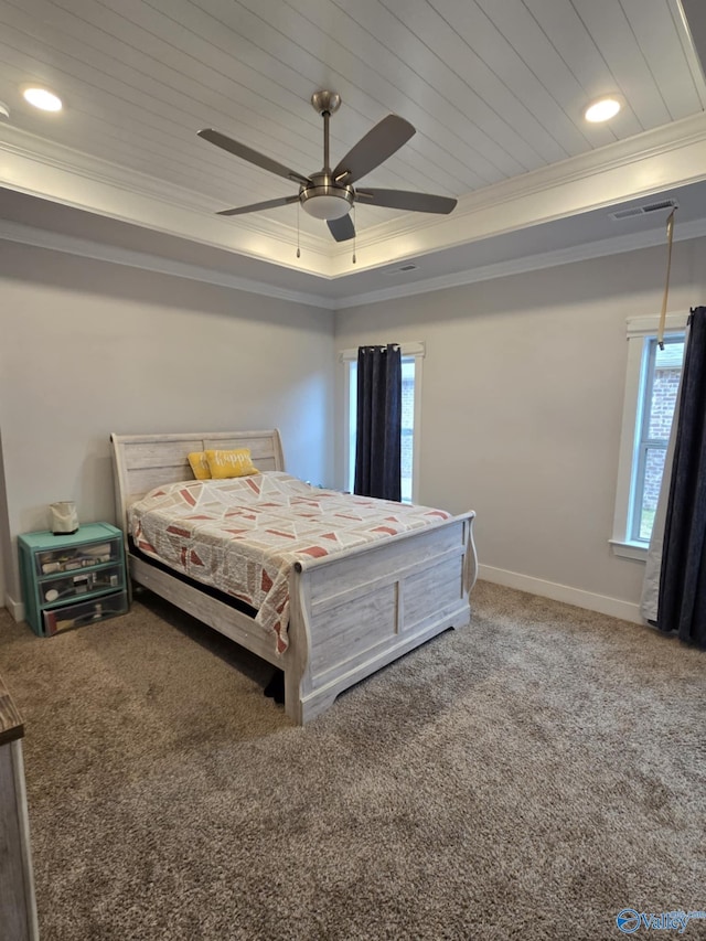 bedroom with visible vents, baseboards, a tray ceiling, ornamental molding, and carpet floors