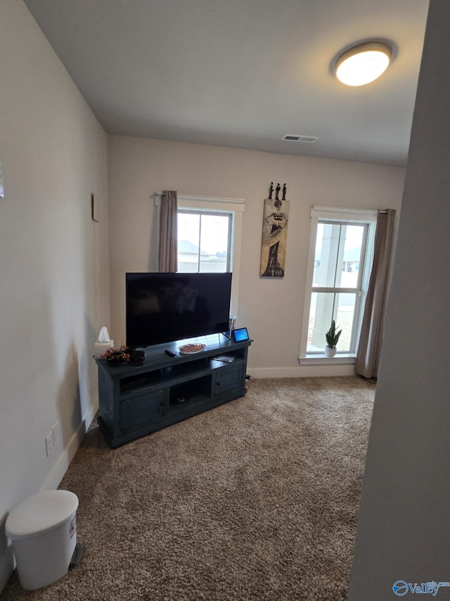 living area with visible vents, a healthy amount of sunlight, baseboards, and carpet