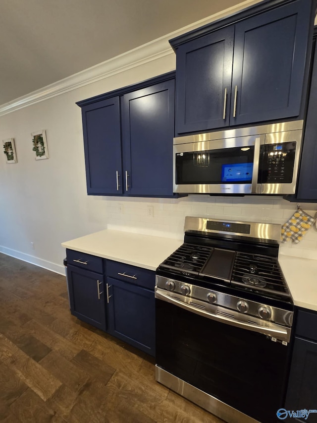 kitchen with ornamental molding, light countertops, appliances with stainless steel finishes, blue cabinets, and backsplash