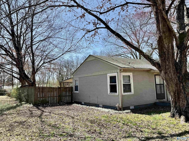 view of side of property with crawl space and fence