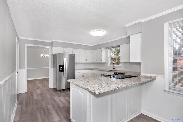 kitchen featuring white cabinetry, stainless steel fridge, light stone countertops, and kitchen peninsula