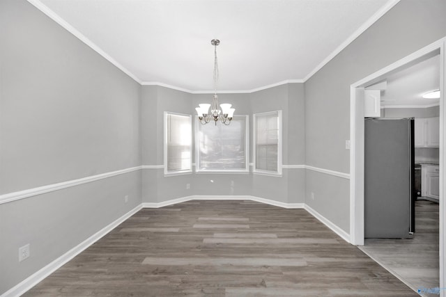 unfurnished dining area featuring crown molding, hardwood / wood-style floors, and a chandelier