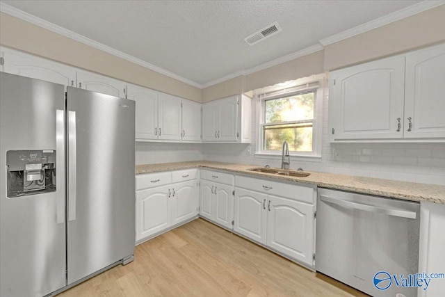 kitchen with white cabinets, appliances with stainless steel finishes, light wood-type flooring, and sink