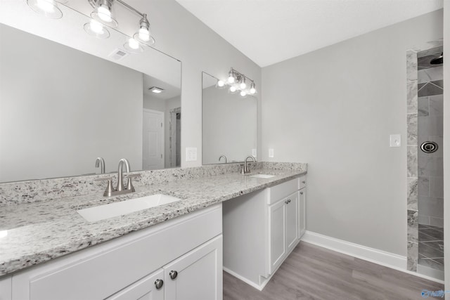 bathroom featuring vanity, hardwood / wood-style flooring, and tiled shower