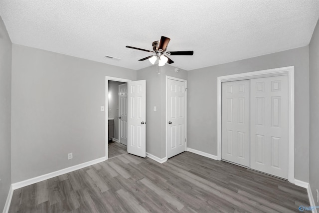 unfurnished bedroom with hardwood / wood-style floors, a closet, a textured ceiling, and ceiling fan