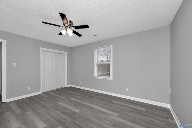 unfurnished bedroom with ceiling fan, dark hardwood / wood-style floors, a closet, and a textured ceiling