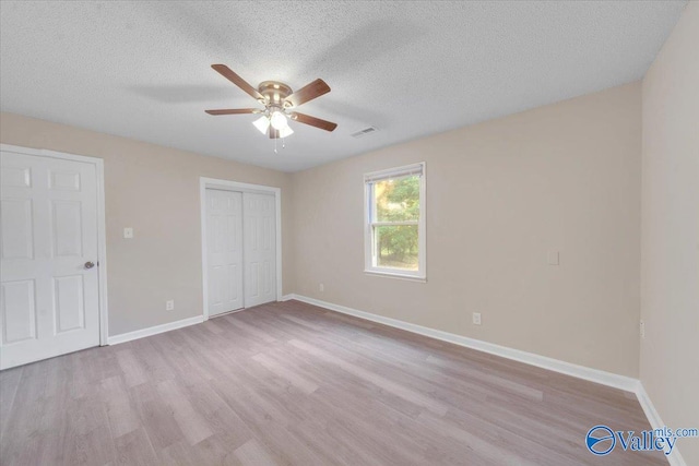 unfurnished bedroom featuring ceiling fan, a closet, light hardwood / wood-style flooring, and a textured ceiling