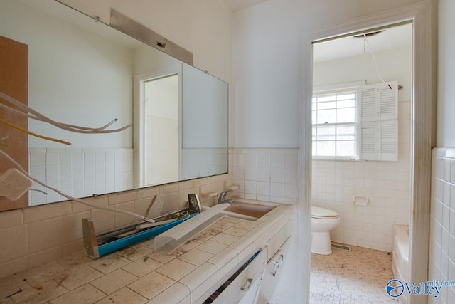 bathroom featuring tile patterned floors, vanity, toilet, and tile walls