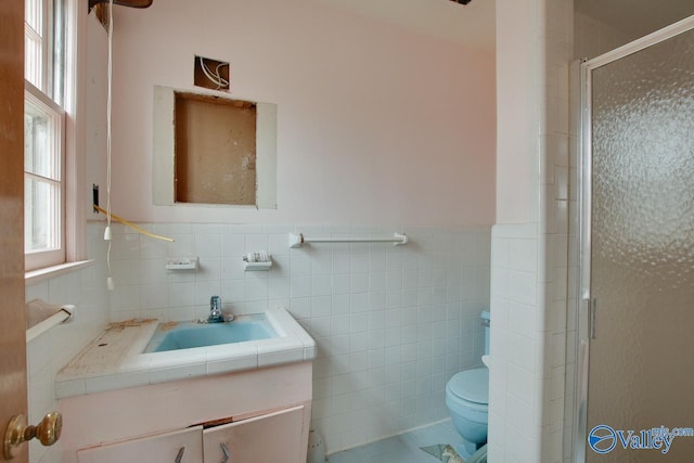 bathroom with a wealth of natural light, an enclosed shower, tile walls, and toilet