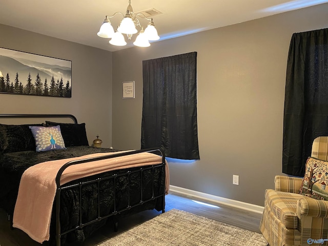 bedroom with wood finished floors, a notable chandelier, and baseboards