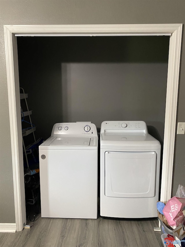 washroom with wood finished floors, washer and dryer, and laundry area