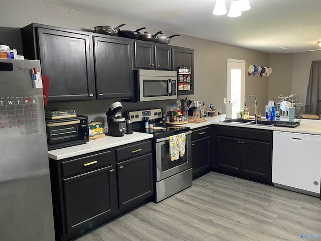 kitchen featuring stainless steel appliances, light wood-type flooring, light countertops, and a sink