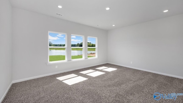 unfurnished room featuring a water view and carpet floors