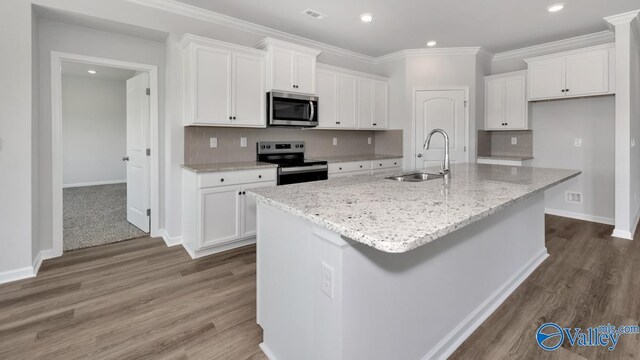 kitchen with an island with sink, stainless steel appliances, white cabinetry, and sink