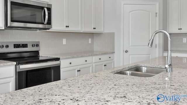 kitchen featuring light stone countertops, sink, white cabinetry, and stainless steel appliances