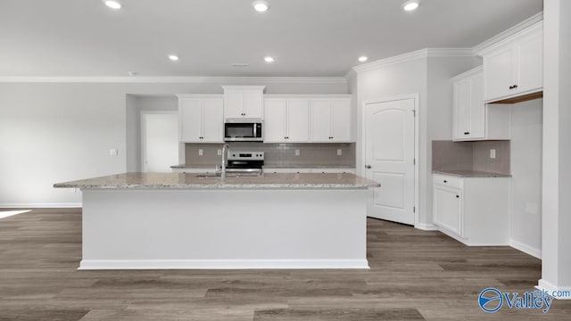 kitchen featuring light stone countertops, hardwood / wood-style floors, white cabinetry, and an island with sink