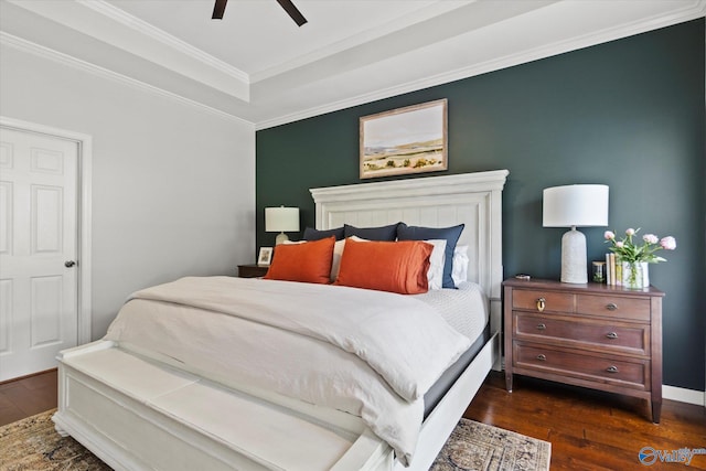 bedroom with dark wood-type flooring, ceiling fan, ornamental molding, and a tray ceiling