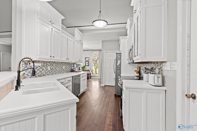 kitchen with appliances with stainless steel finishes, pendant lighting, sink, white cabinets, and decorative backsplash