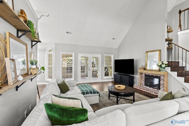 living room featuring wood-type flooring, a brick fireplace, high vaulted ceiling, and french doors