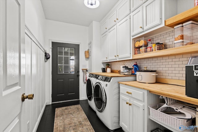 washroom with cabinets, separate washer and dryer, and dark tile patterned floors