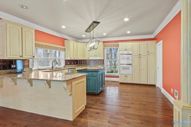 kitchen featuring double oven, cream cabinets, and a peninsula