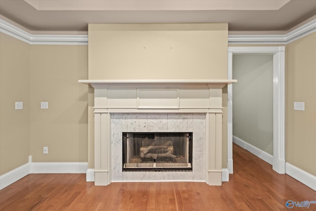 interior details with ornamental molding, wood finished floors, a tile fireplace, and baseboards