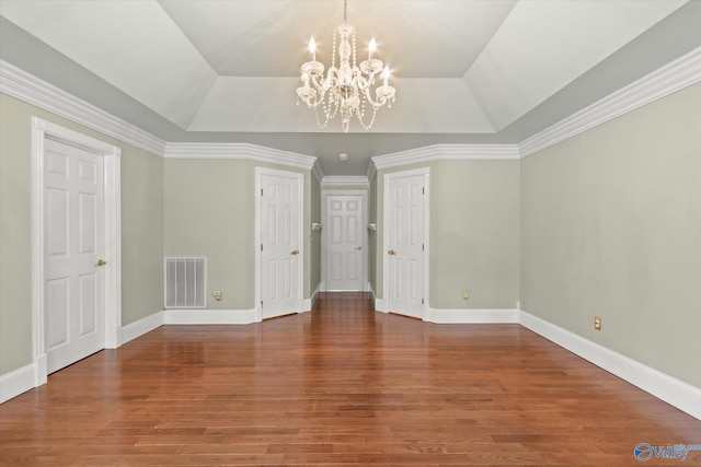 interior space with baseboards, visible vents, a raised ceiling, and wood finished floors