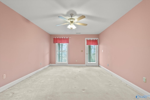 spare room with light colored carpet, ceiling fan, visible vents, and baseboards