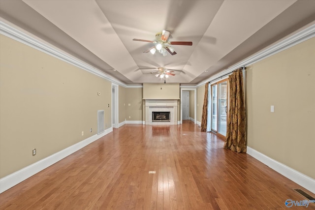 unfurnished living room featuring a fireplace, visible vents, baseboards, light wood finished floors, and a raised ceiling