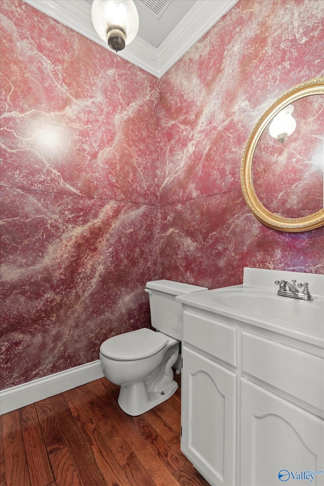 bathroom with crown molding, toilet, vanity, wood finished floors, and baseboards