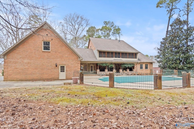 rear view of property featuring a fenced in pool, a patio area, fence, and brick siding