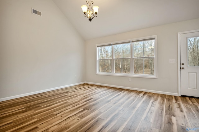 foyer entrance featuring lofted ceiling, a notable chandelier, and light hardwood / wood-style flooring