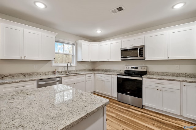 kitchen featuring sink, light hardwood / wood-style flooring, stainless steel appliances, light stone countertops, and white cabinets