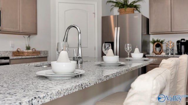 room details featuring stainless steel fridge, light stone counters, sink, and light brown cabinets