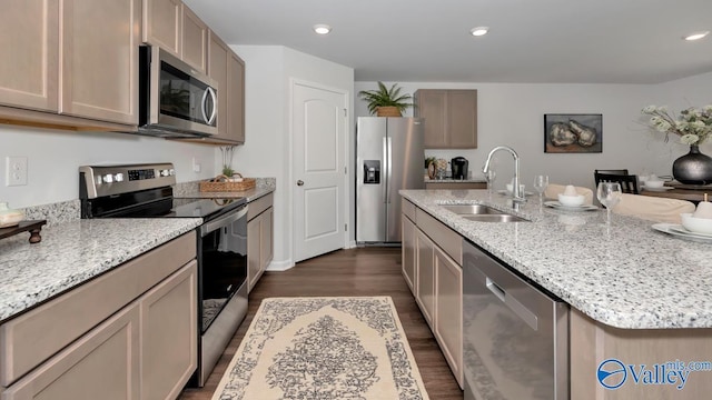 kitchen featuring sink, light stone counters, dark hardwood / wood-style flooring, an island with sink, and appliances with stainless steel finishes