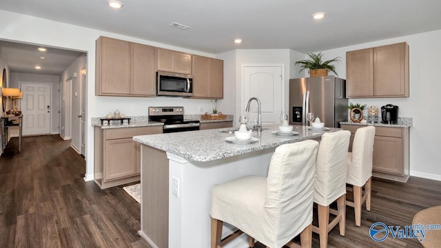 kitchen with a breakfast bar, a kitchen island with sink, sink, dark hardwood / wood-style floors, and stainless steel appliances