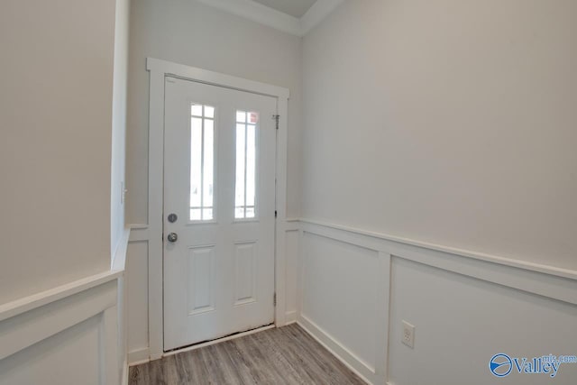 entryway featuring light wood-type flooring, a wainscoted wall, and a decorative wall